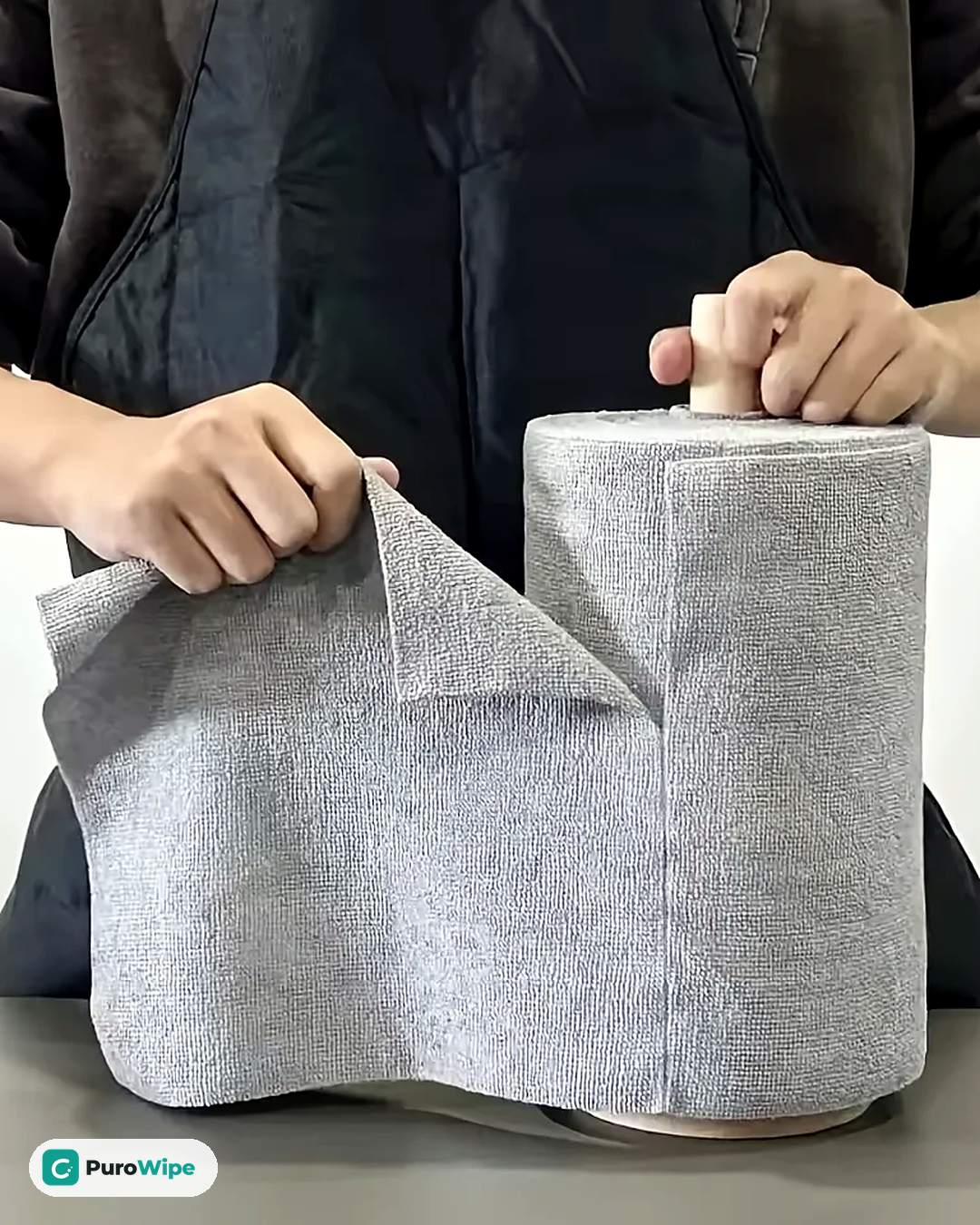 Hands tearing a gray microfiber sheet off the PuroWipe roll